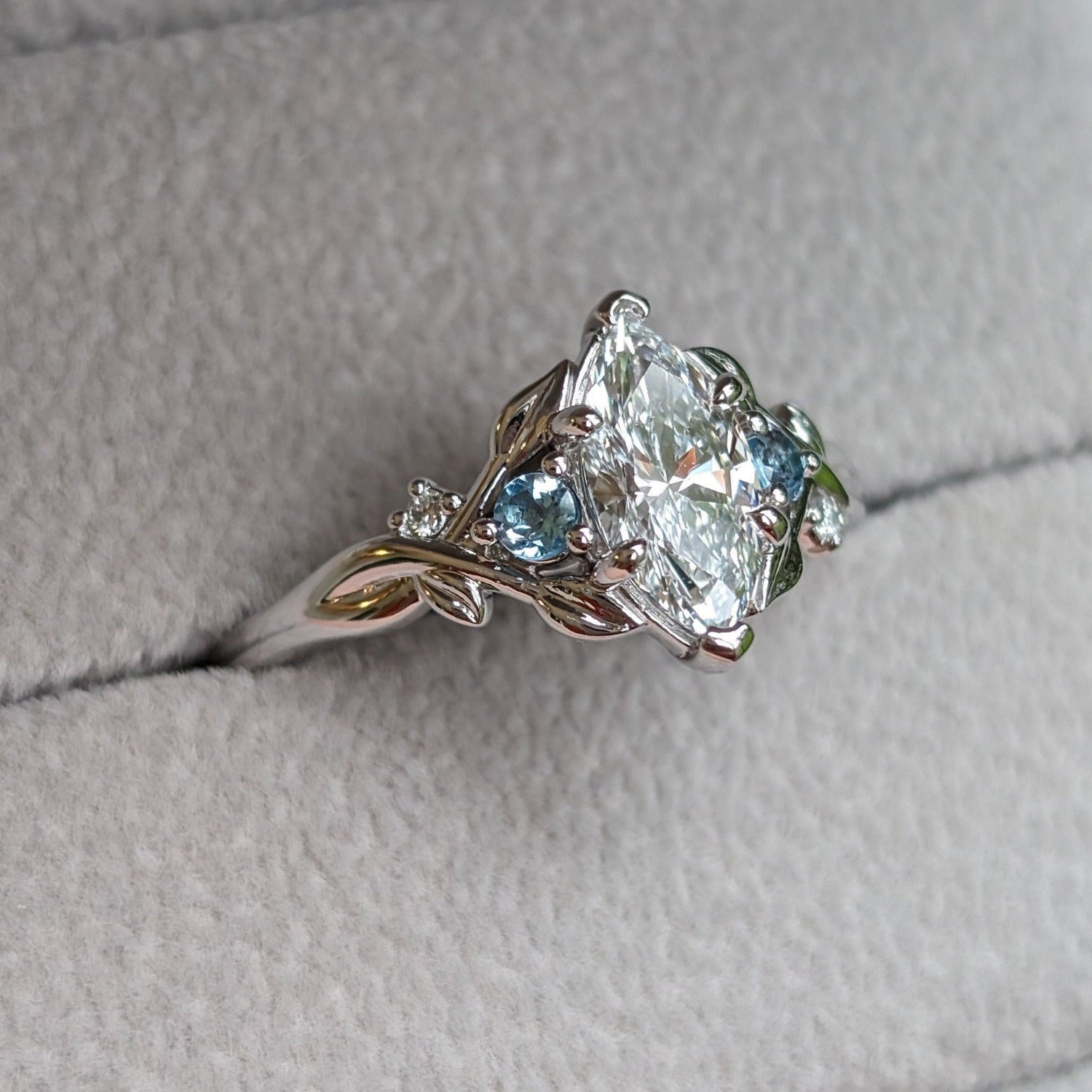 Maquise diamond engagement ring with blue topaz accents.  Leaves and vines on band