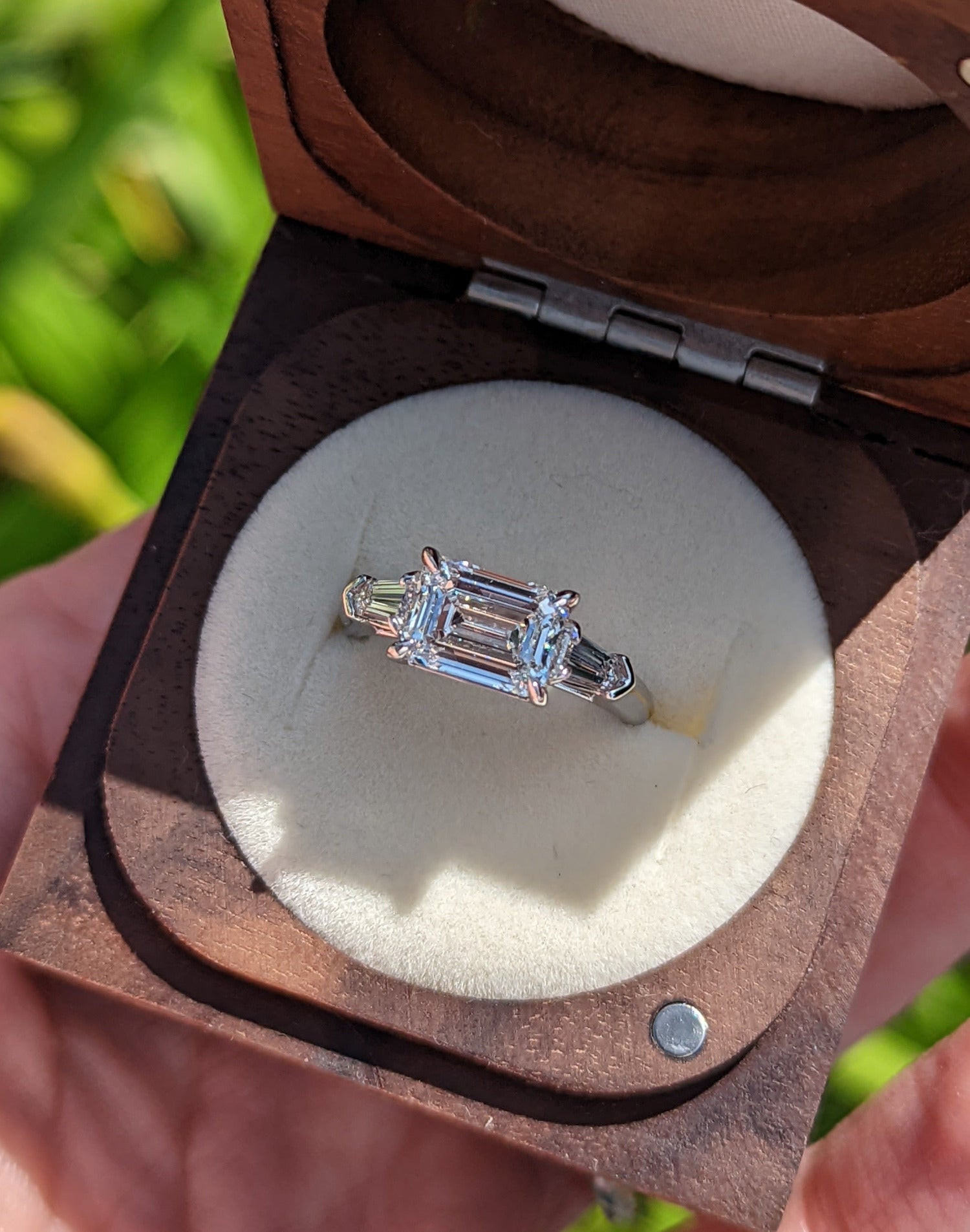 Emerald cut diamond engagement ring with tapered bullet diamond accents.  Center stone set east to west.