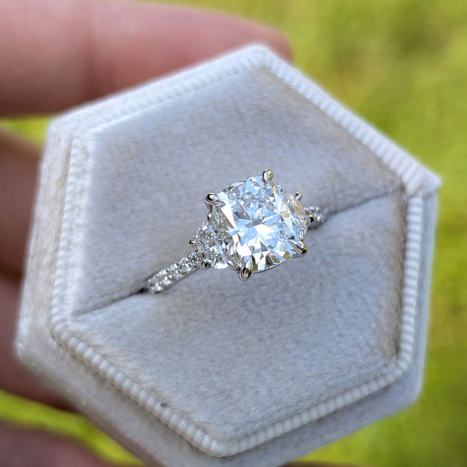 Elongated cushion cut diamond with half moon diamond accents in platinum
